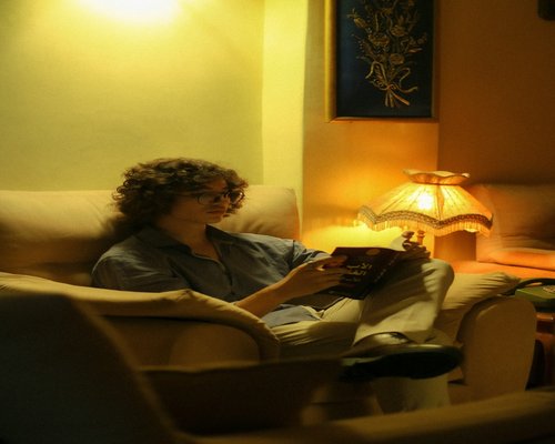 A person enjoying a book on a comfortable sofa with warm ambient lighting
